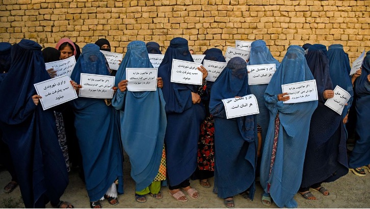 Afghan women in burqas holding placards to protest for their right to education Aug, 2023